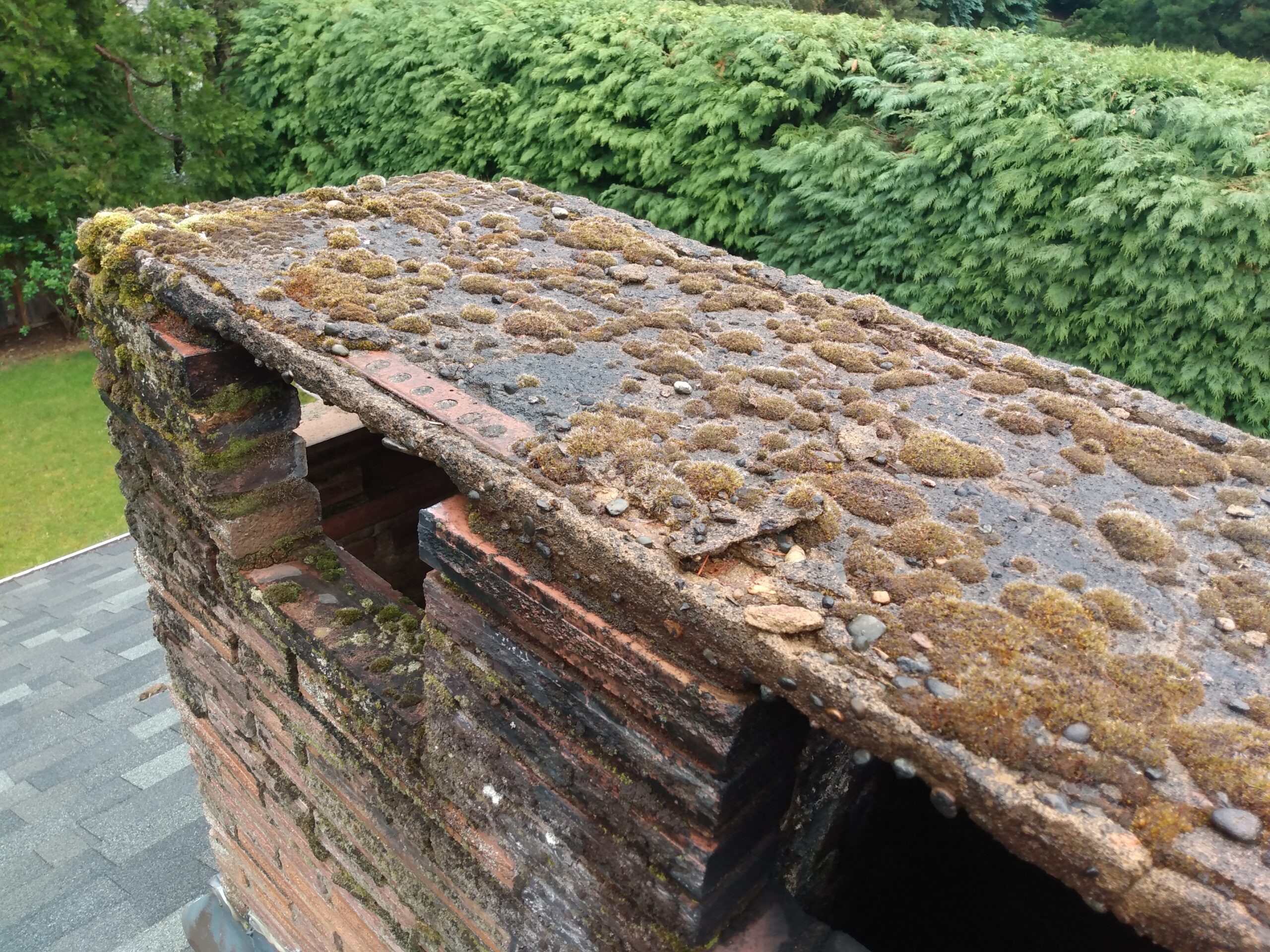 Weather-damaged concrete cap on top of a residential chimney.